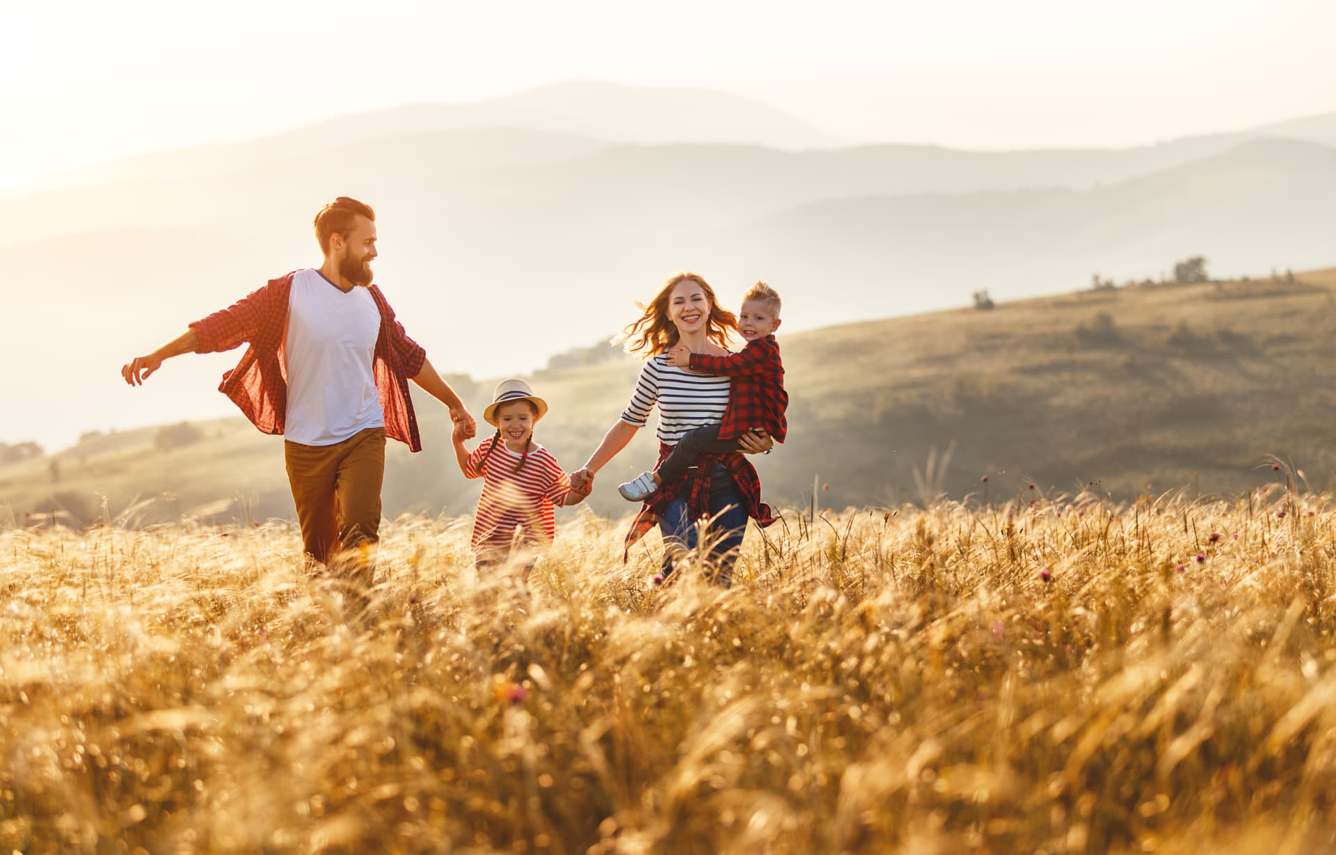 A happy family walking together through a sunlit meadow with rolling hills